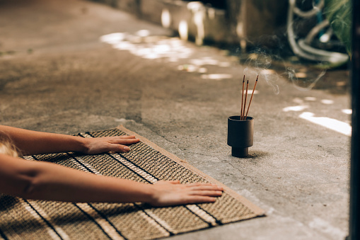 Incense sticks burning and making a woman's yoga practice even more enjoyable.