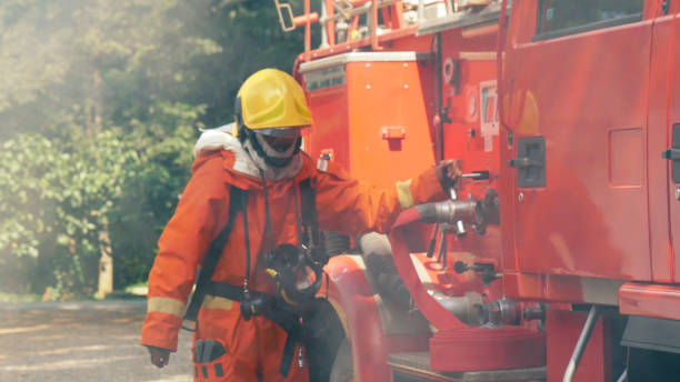 istock Firefighter fighting with flame using fire hose chemical water foam spray engine. Fireman wear hard hat, body safe suit uniform for protection. Rescue training in fire fighting extinguisher 1259297688