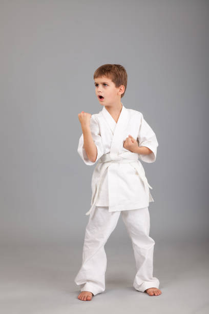 istock Karate boy in white kimono fighting 1259325217