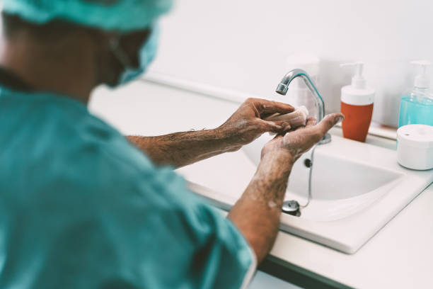 cirujano lavándose las manos antes de operar al paciente en el hospital - trabajador médico preparándose para luchar contra la pandemia del virus corona - concepto de cuidado de la salud e higiene - scrubbing up fotografías e imágenes de stock