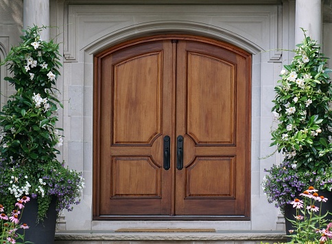 A large brown wooden door on a modern white church building.