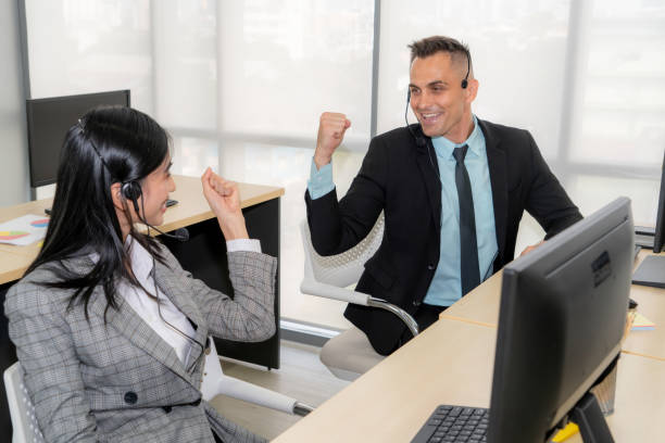 istock Business people wearing headset celebrate working in office 1259381413