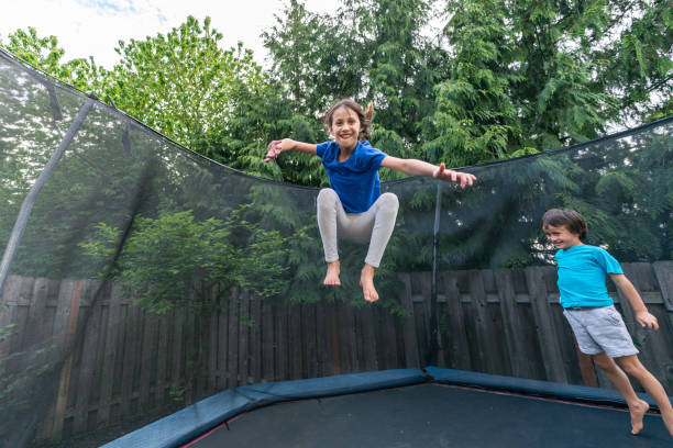 istock Children jumping on a trampoline in a backyard without parents around 1259389262