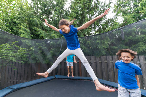 istock Children jumping on a trampoline in a backyard without parents around 1259389273