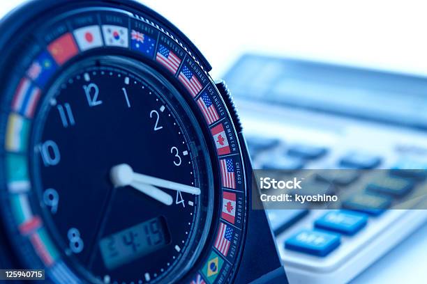 Blue Tinted Image Of World Time Clock With Calculator Stock Photo - Download Image Now