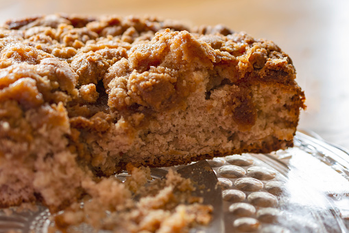 Close up of a cut coffee cake on a glass platter.