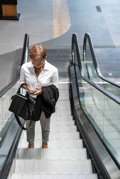 istock Business woman using phone on escalator 1259441938