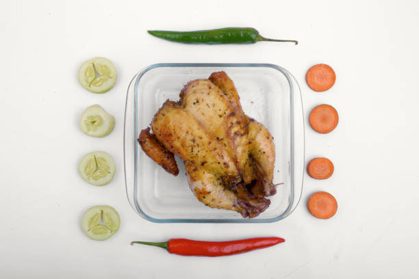 Roasted chicken in glass baking tray with vegetables isolated over white background