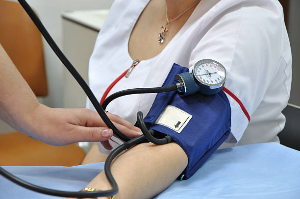 A woman having her blood pressure taken manually stock photo