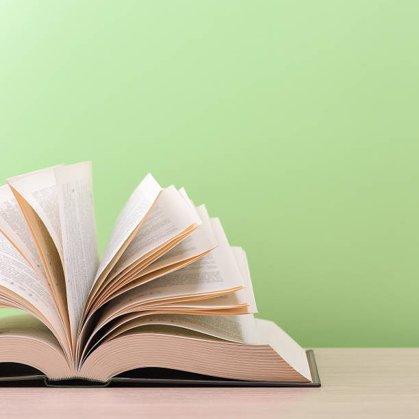 istock The book is open, lying on the table, sheets fanned out on a green background. 1259559093