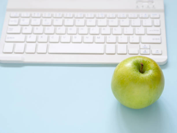 istock Close up green apple and keyboard on blue workplace desk table. 1259591694