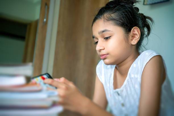 istock Asian/Indian little girl using mobile phone in bad sitting posture. 1259601103