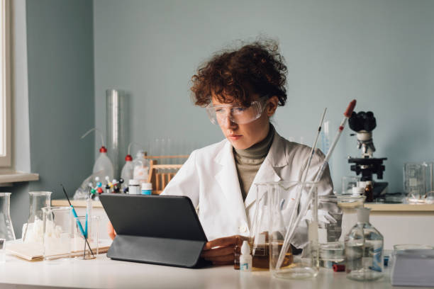 Woman Scientist in a Lab Coat Using a Digital Tablet During Research