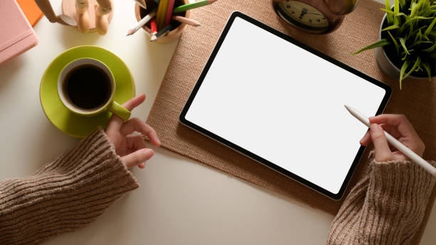istock Female hand using tablet with clipping path and holding coffee cup on office desk 1259612049