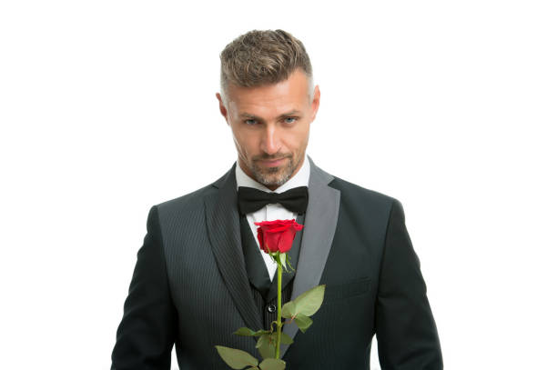 女性の日を祝う。ハンサムな男は赤いバラを保持します。女性の日のための花。フォーマルウェアの学士号。国際女性の日。3月8日。女性の日に花の贈り物 - single flower bouquet flower holidays and celebrations ストックフォトと画像
