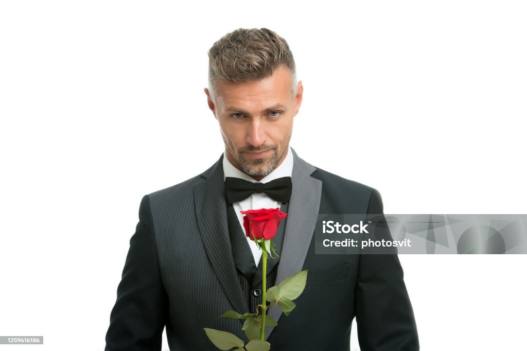Celebrating womens day. Handsome man hold red rose. Flowers for womens day. Bachelor in formalwear. International womens day. March 8. Floral gift on womens day Celebrating womens day. Handsome man hold red rose. Flowers for womens day. Bachelor in formalwear. International womens day. March 8. Floral gift on womens day. Bachelor Stock Photo