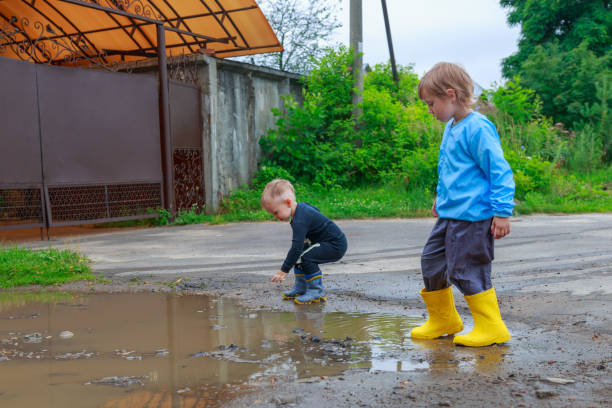 istock .children in rubber boots and raincoats play in a puddle 1259682517