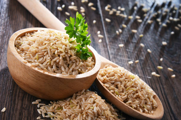 composizione con ciotola di riso integrale su tavolo di legno - brown rice rice healthy eating organic foto e immagini stock