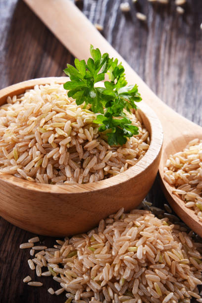 composición con cuenco de arroz integral sobre mesa de madera - dishware brown rice rice variation fotografías e imágenes de stock