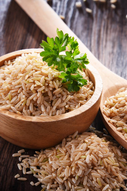 composizione con ciotola di riso integrale su tavolo di legno - brown rice rice healthy eating organic foto e immagini stock