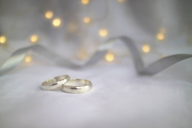 Wedding rings with grey ribbon white A pair of wedding rings with lamp  background 50th anniversary photos stock pictures, royalty-free photos & images