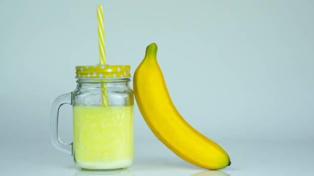 banana shake na szklanym słoiku z bananem obok - smoothie banana smoothie milk shake banana zdjęcia i obrazy z banku zdjęć