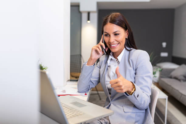istock Business woman usingmobile phone, looking at laptop screen, chatting, reading or writing email, sitting in home office, female student doing homework, working on research project online 1259743343