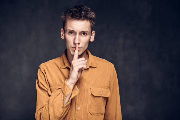 istock caucasian man show silence sign on dark background 1259753375