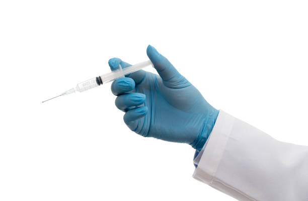 Scientist's hand wearing blue gloves against white background and holding Covid-19 vaccine. stock photo