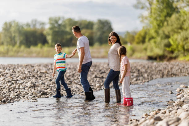 istock Happy family talking while walking through water on the riverbank. 1259804180