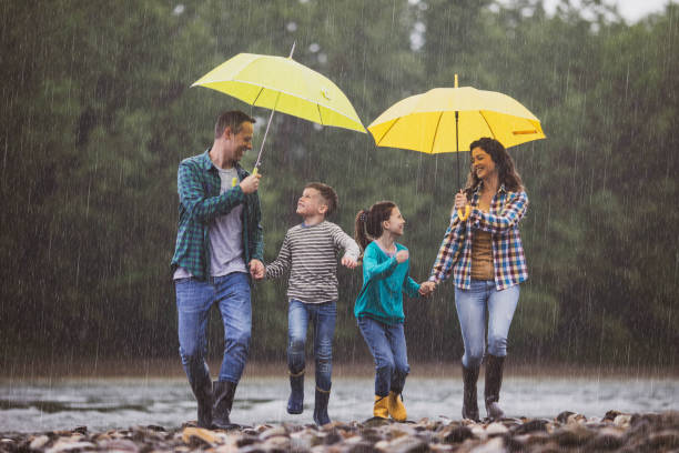 istock Carefree family having fun while running on rain at riverbank. 1259807809