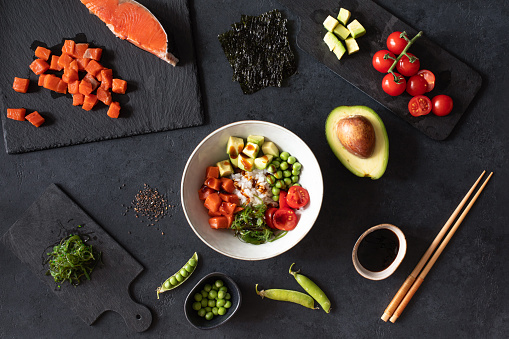 Ingredients for Poke bowl with raw fresh salmon on black background with copy space. Top view.