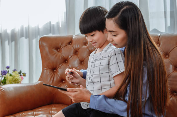 istock Asian mother work home together with son. Mom teaching kid for online learning education. New normal lifestyle and family activity. 1259845601