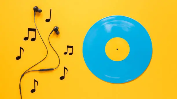 Musical notes and earphones with copy. Flat lay blue vinyl disc with yellow background . minimal image. concept  image.