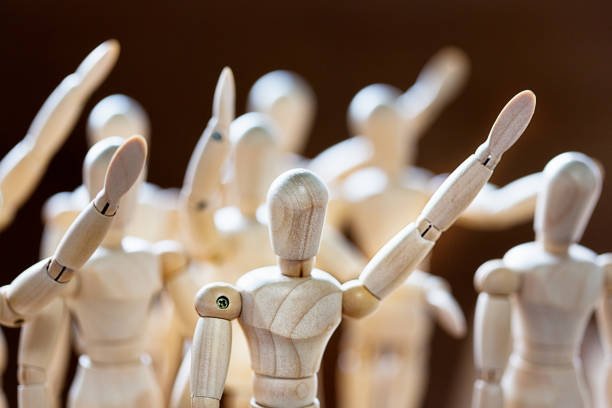 istock Crowd of lay figures with hands raised, volunteering or asking to speak 1259848278