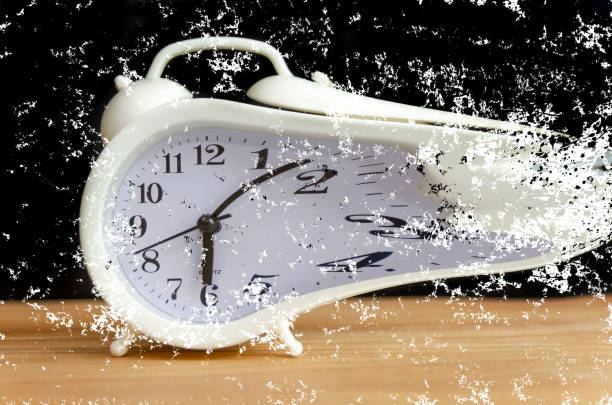 istock white alarm clock stands on a wooden table against a black wall, copy space. white alarm clock disintegrates into particles. concept of transience of time. 1259880863