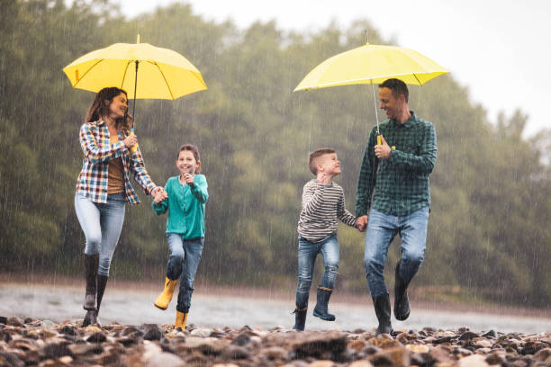 istock Happy family having fun while running on a rainy day at riverbank. 1259882613