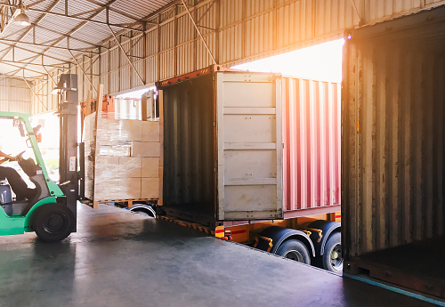 El conductor de la carretilla elevadora carga mercancías de palet de carga en un contenedor de camiones en el muelle del almacén. Logística y transporte de envío de entrega de la industria de carga de carga. photo