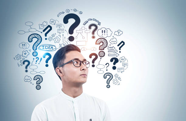 istock Asian man in glasses, question marks 1259894983
