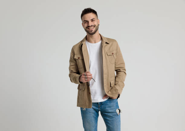 istock happy young casual guy in jacket holding hand in pocket 1259895540