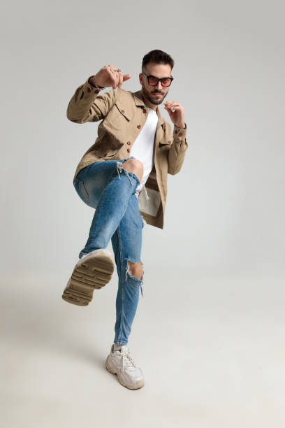 istock young casual man in jacket holding leg up and kicking 1259900954