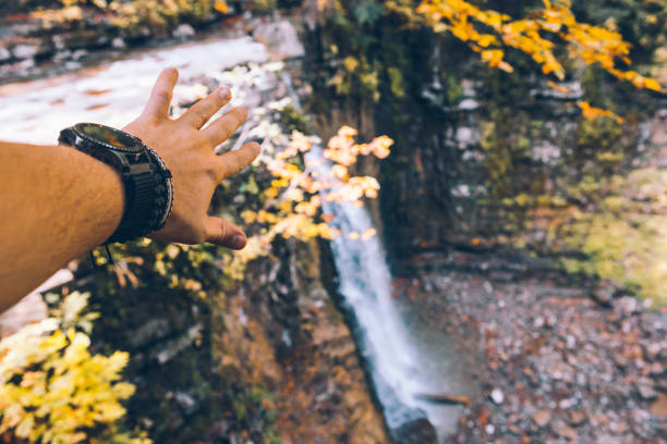first person view man hands showing waterfall hiking concept autumn season