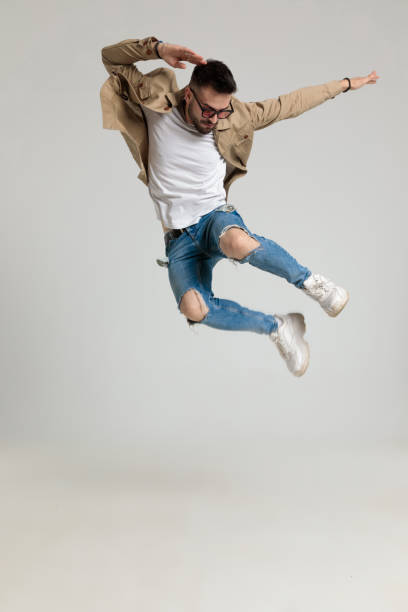 istock cool young man in jacket looking down and jumping 1259904243