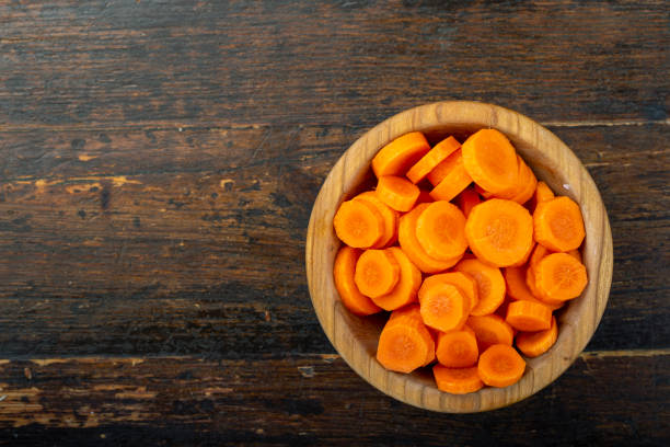 sliced carrots in a bowl on a wooden background. vegetable, ingredient and staple food. - carrot isolated white carotene imagens e fotografias de stock