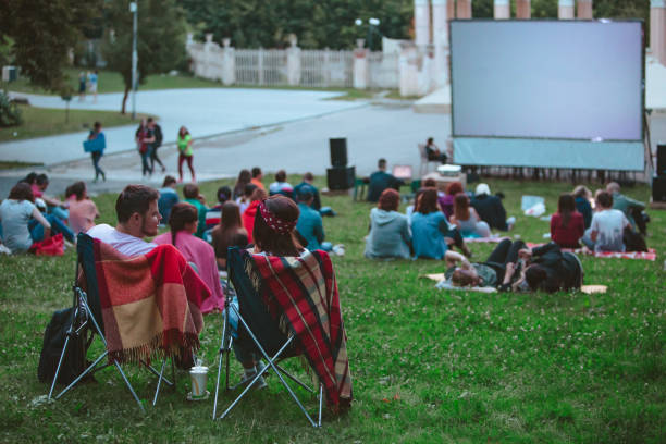 couples s’asseyant dans des chaises de camp devant l’écran de film au cinéma en plein air - computer chip photos et images de collection