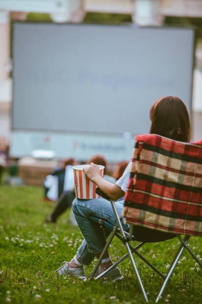 femme s’asseyant dans la chaise de camping regardant le film au cinéma en plein air - computer chip photos et images de collection