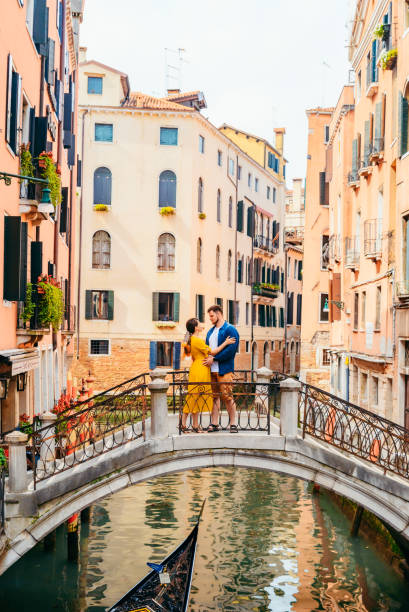 couple standing on the bridge crossing venice canals