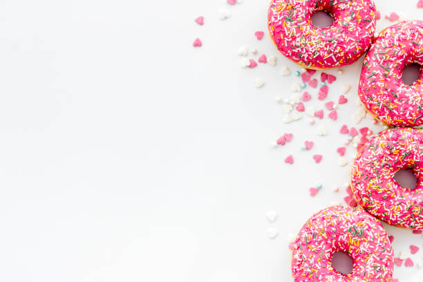 istock Pink berry donuts flat lay, top view. Glazed and sprinkles doughnuts 1259918502