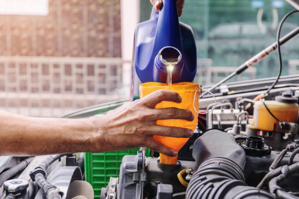 istock Car mechanic is adding oil to the engine. 1259919050