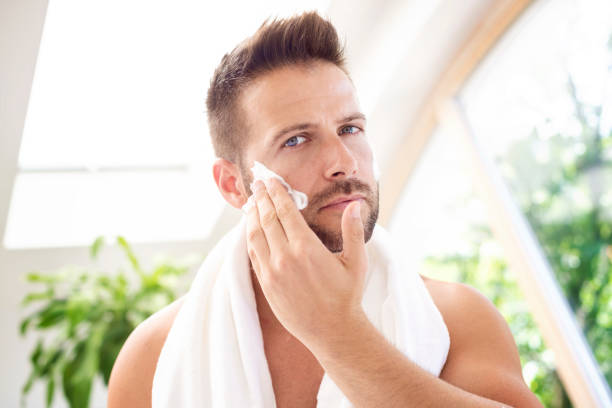 istock Handsome man standing at bathroom mirror and applying shaving foam 1259935216